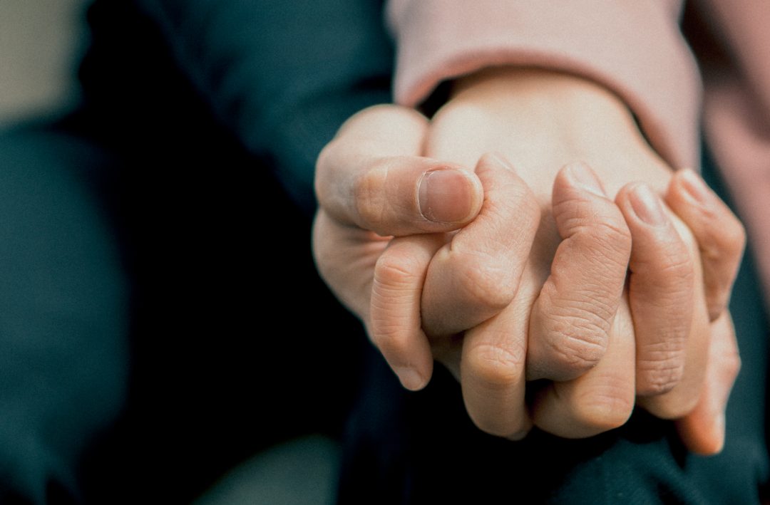 Two people holding hands in support
